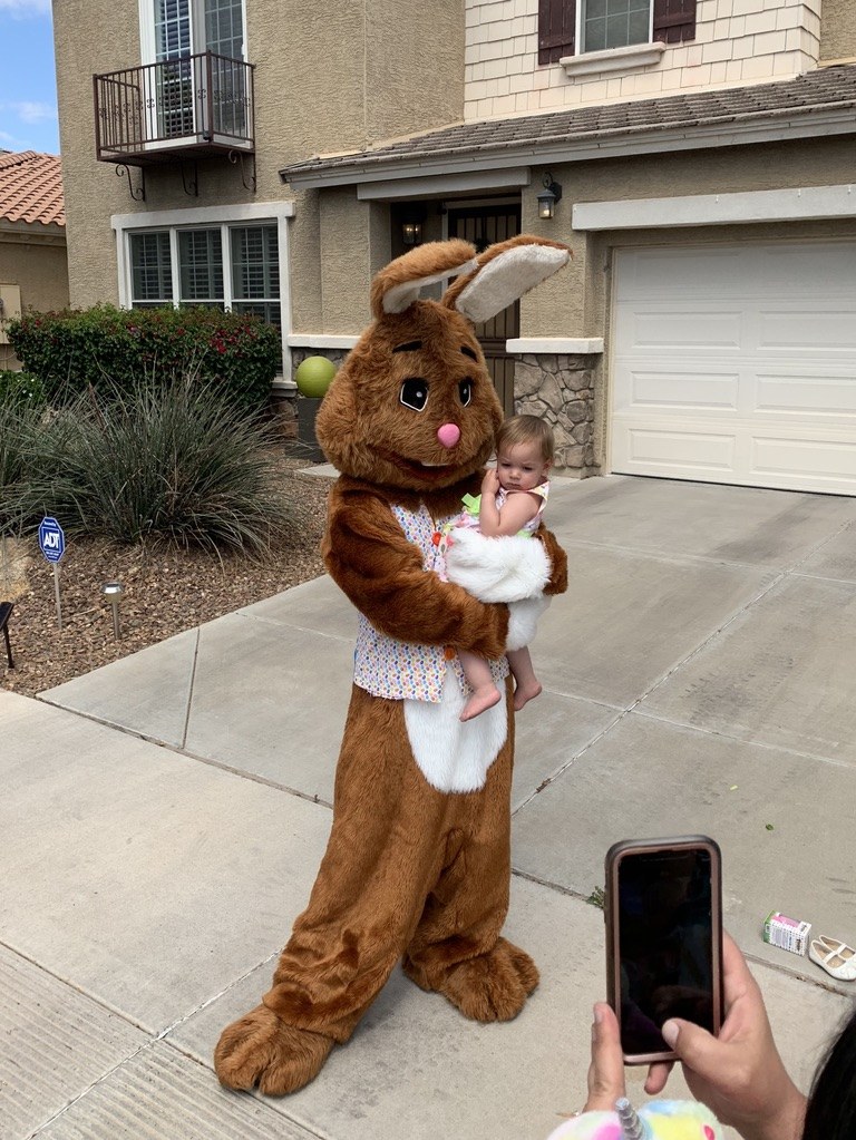 Easter Bunny holding a child outside a home